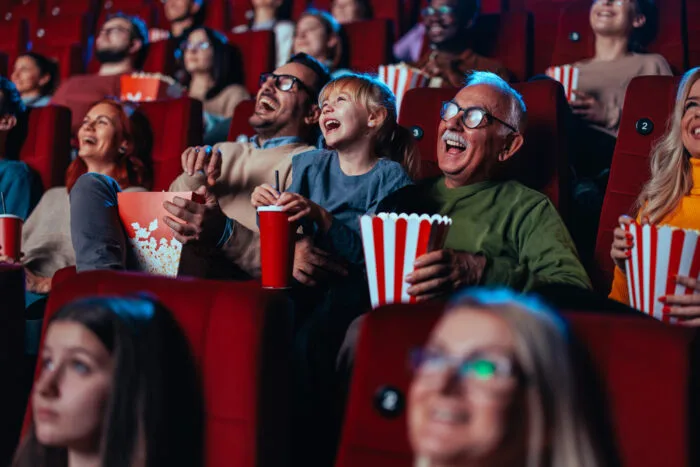 Skrattande människor som äter popcorn i biosalong.