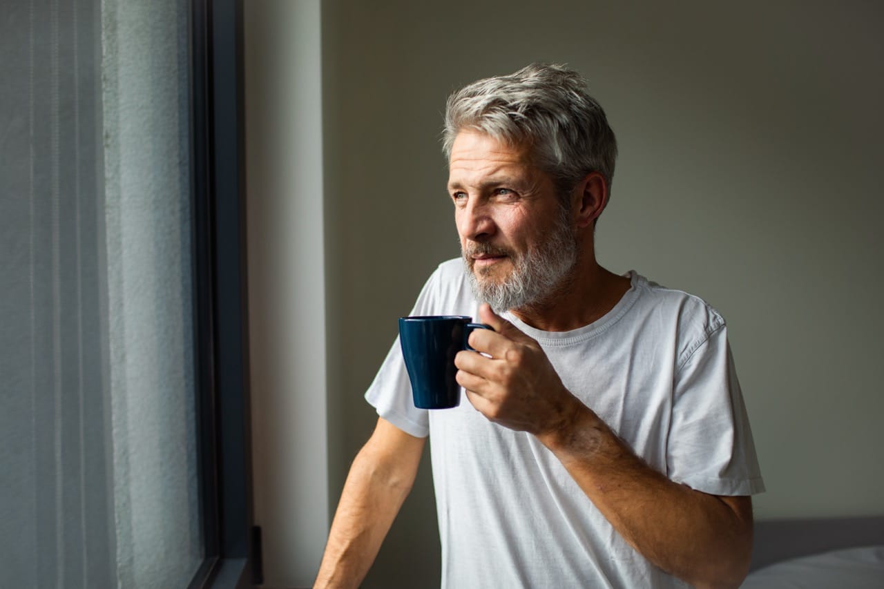 Man står med i ett rum med en kaffemugg i handen.